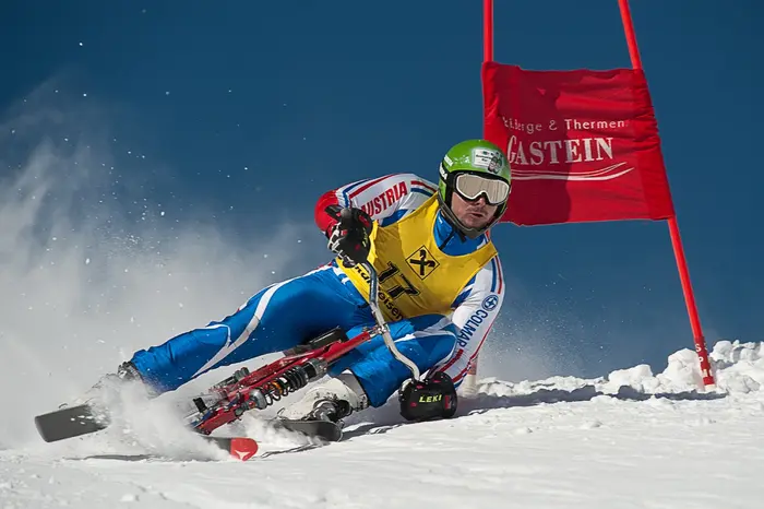 Skibobfahrer in dynamischer Kurvenlage vor einem roten Tor